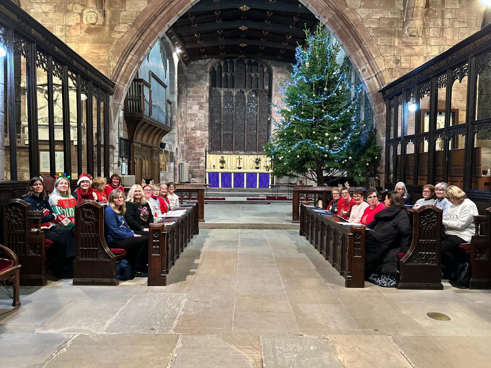 Choir members seated together in the choir stalls at Malpas Church, decorated for Christmas.